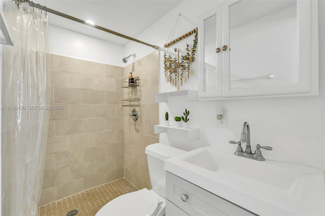 Bathroom featuring a vanity with a white composite sink, brushed nickel widespread faucet, and built-in mirrored medicine cabinet
