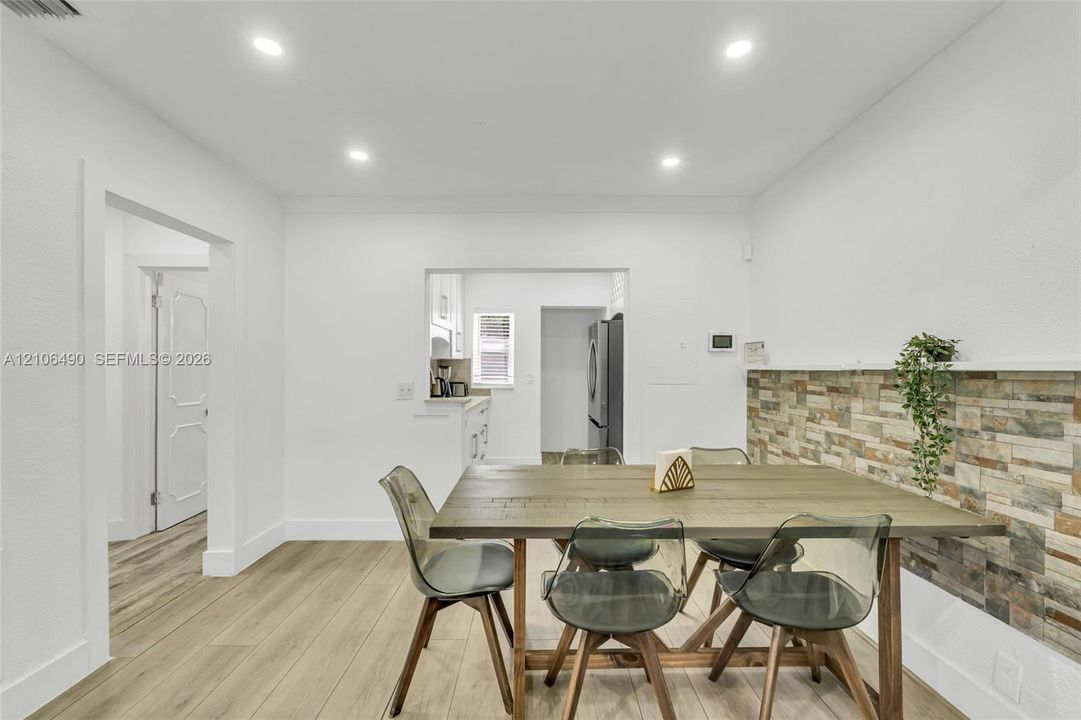 Dining area featuring wood-finish flooring, recessed lighting, and a textured stone-finish accent wall