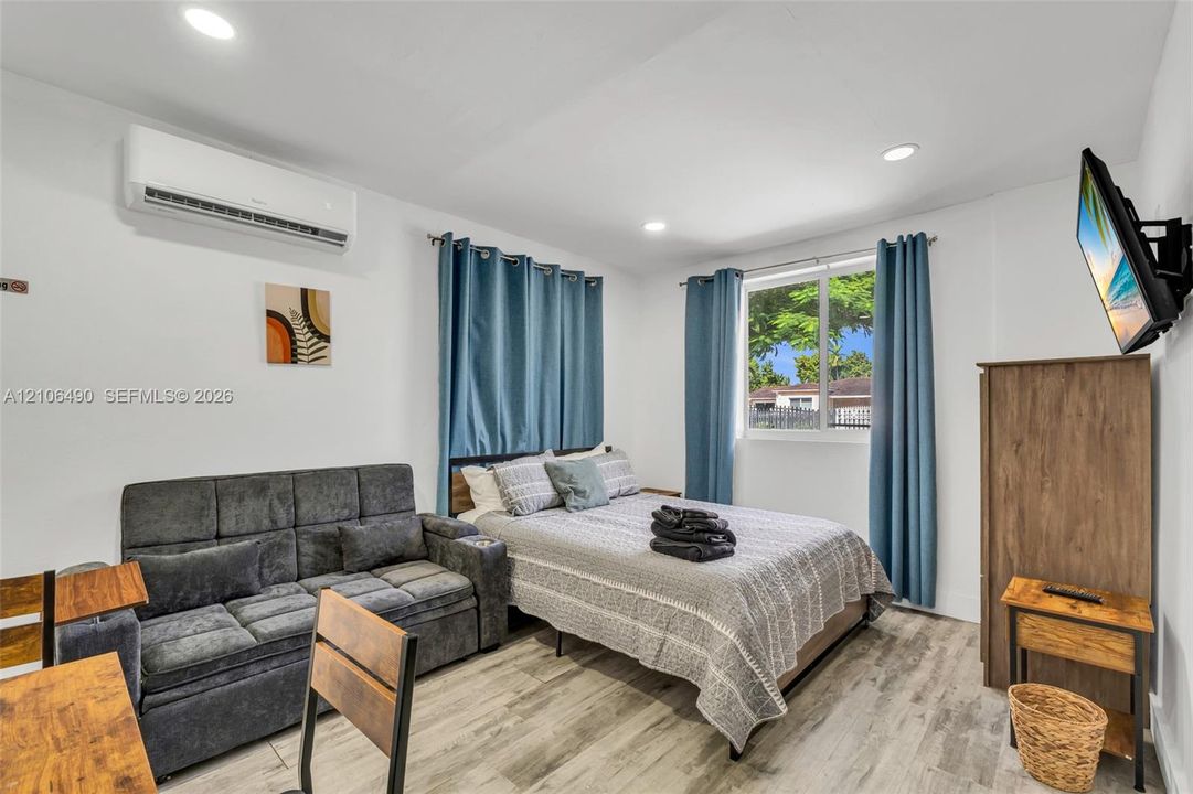 Neutral-toned wood-finish flooring, recessed lighting, and a wall-mounted mini-split cooling system