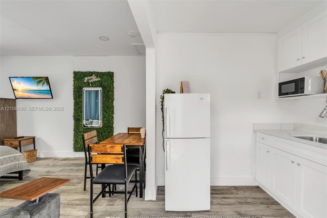 Kitchen featuring white shaker-style cabinetry, a built-in microwave, a top-freezer refrigerator, and wood-finish flooring