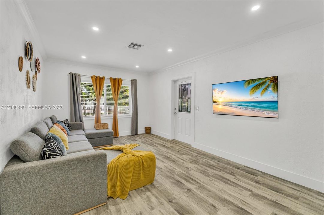 Wood-finish flooring, recessed lighting, crown molding, and a paneled entry door with decorative glass inlay