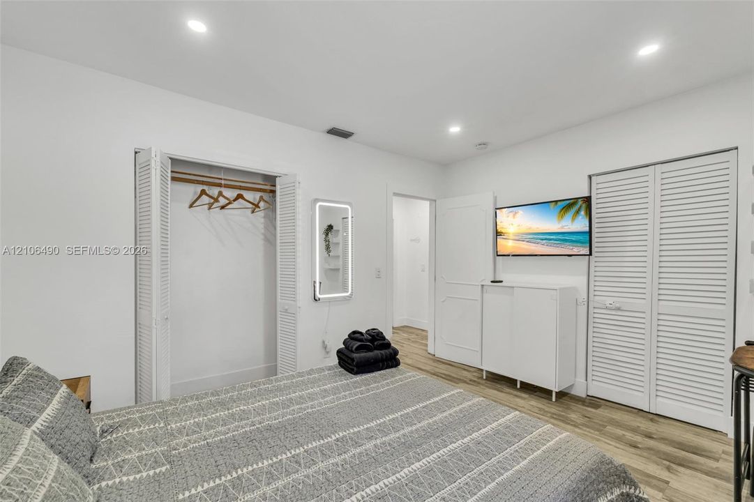 Room featuring wood-finish flooring, recessed lighting, and double-closet storage with louvered doors