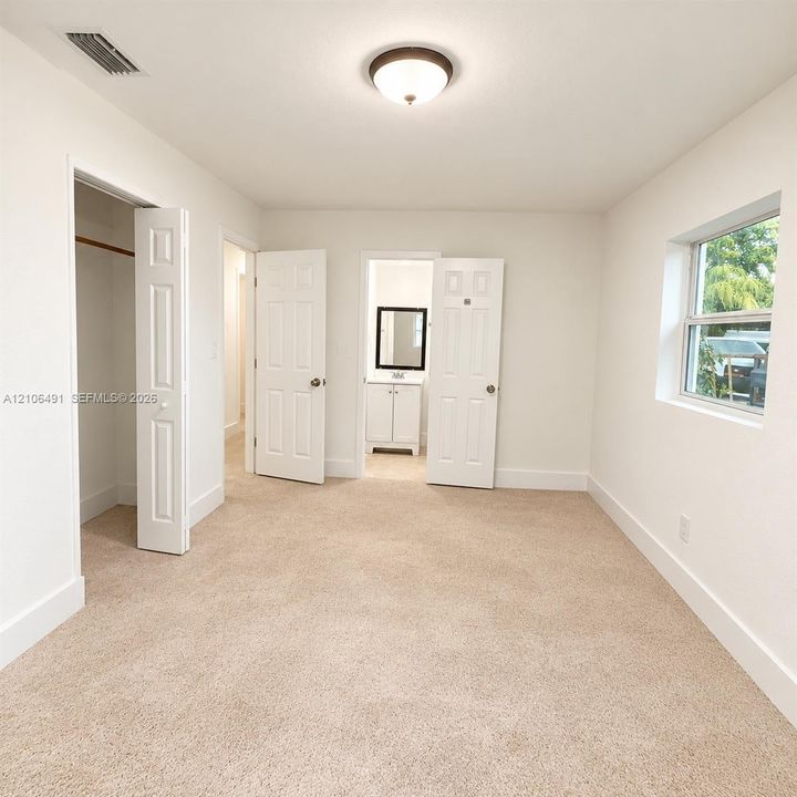 Neutral wall-to-wall carpeting, flush-mount ceiling lighting, multi-panel interior doors, and a closet with a built-in rod