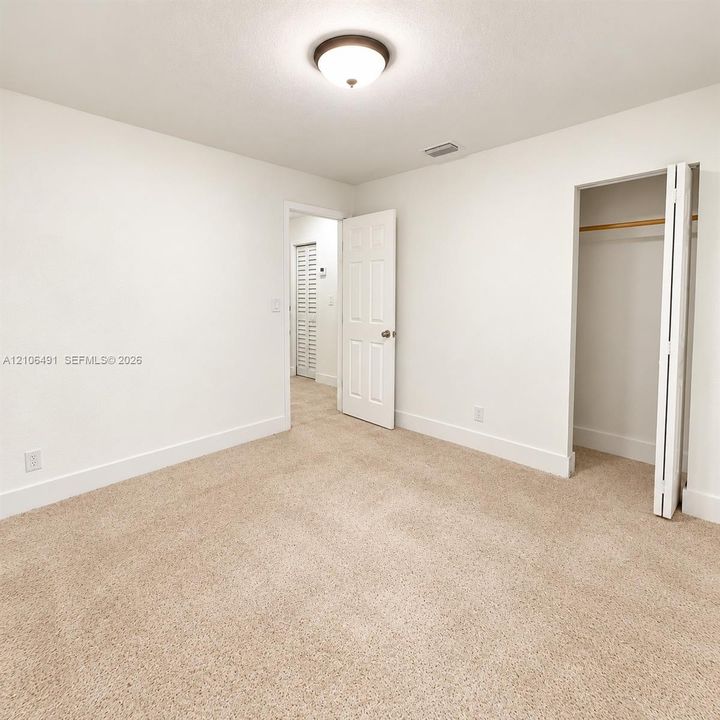 Neutral-toned carpeted flooring, flush-mount ceiling lighting, and a closet with bifold doors