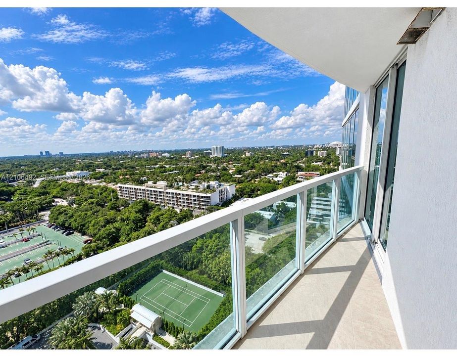Private balcony with a glass and metal railing, concrete flooring, and full-height sliding glass doors