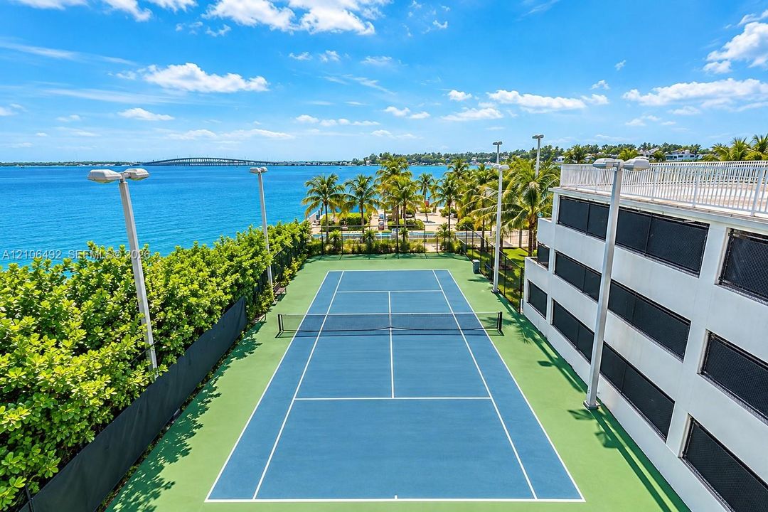 Tennis court featuring a hard surface, perimeter lighting, and surrounding privacy screening