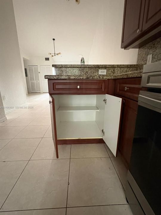 Kitchen featuring cabinetry with a dark wood finish, stone-surfaced countertops, and neutral-toned tile flooring
