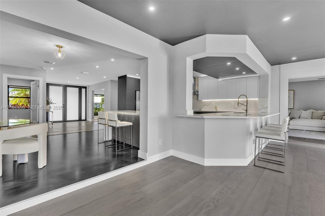 Open-concept kitchen featuring flat-panel cabinetry, a peninsula with stone-finish countertops, recessed lighting, and wood-finish flooring