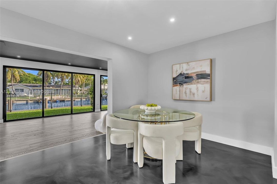 Large-format sliding glass doors, polished concrete flooring, recessed lighting, and water-front exterior exposure