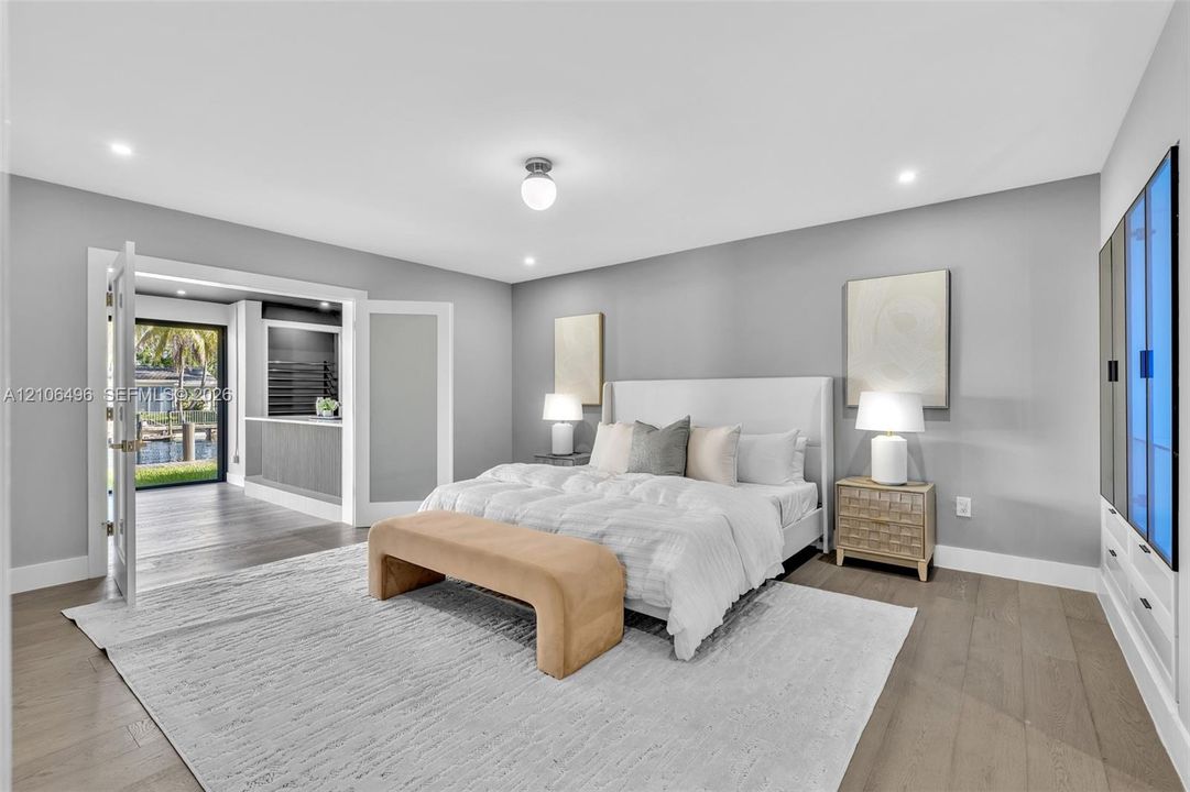 Interior space featuring wood-finish flooring, recessed lighting, built-in cabinetry with glass-front accents, and double glass-paneled doors opening to an exterior area