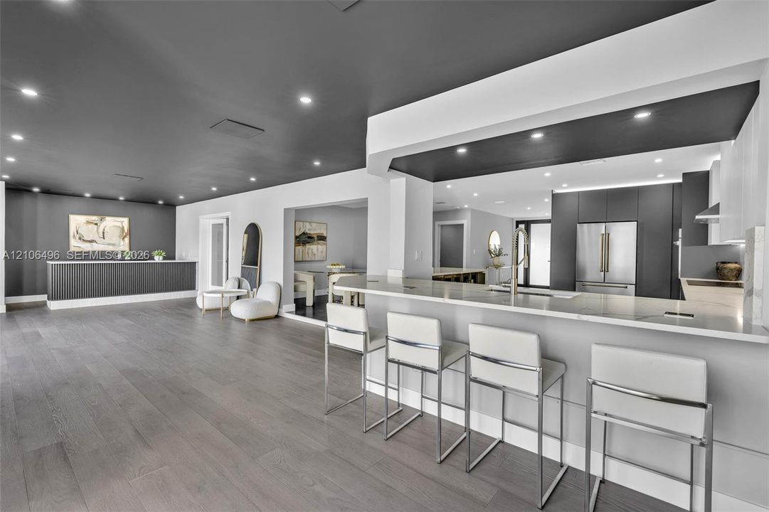 Open concept kitchen featuring a breakfast bar with stone-finish countertops, flat-panel cabinetry, recessed lighting, and wood-finish flooring