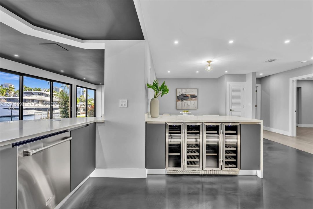 Wet bar featuring integrated stainless steel under-counter wine refrigerators, solid-surface countertops, recessed lighting, and large-format floor tiling
