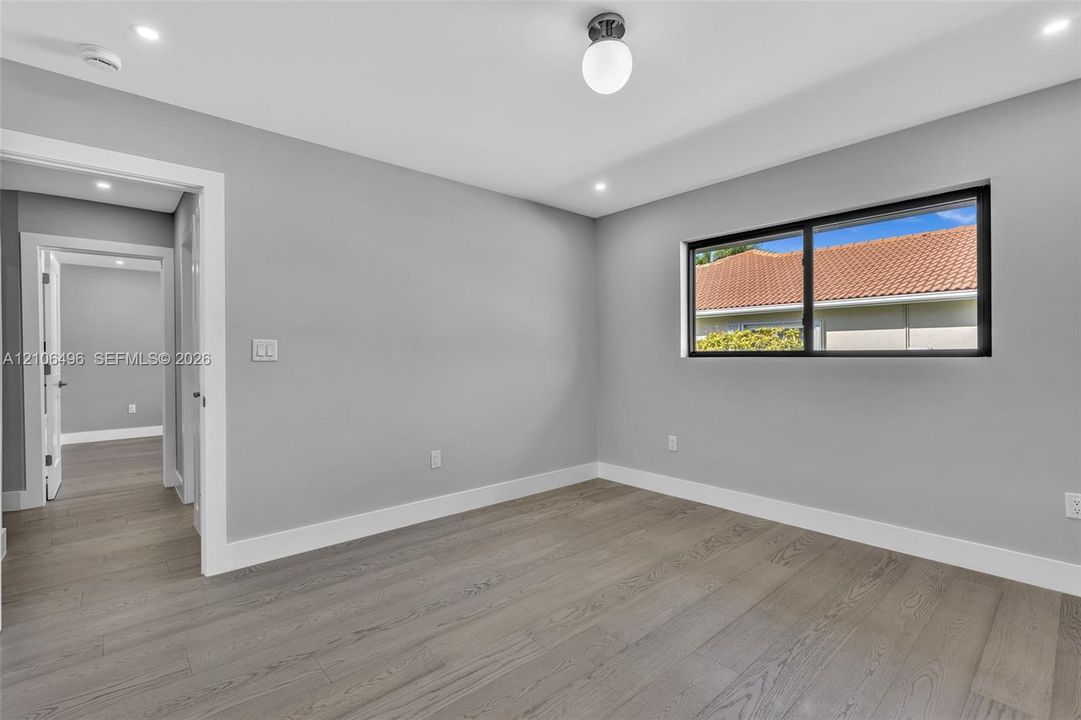 Interior space featuring wood-finish flooring, neutral wall paint, recessed lighting, a globe-style light fixture, and a black-framed window