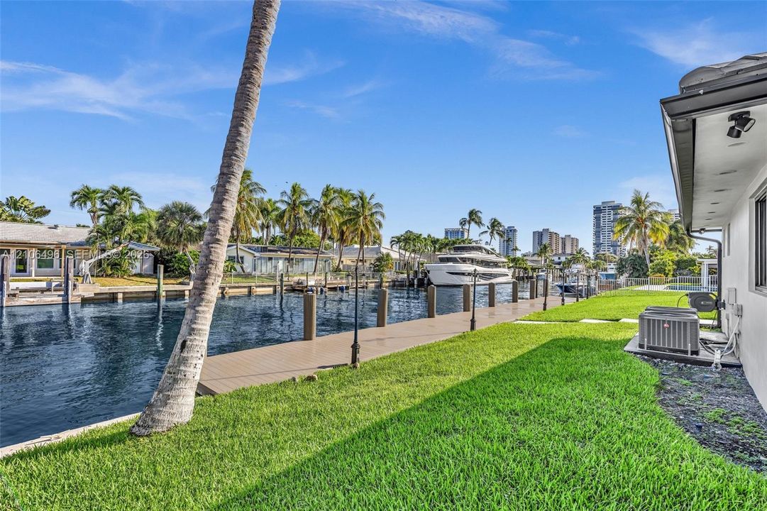 Waterfront property featuring a private dock, bulkhead, and manicured lawn