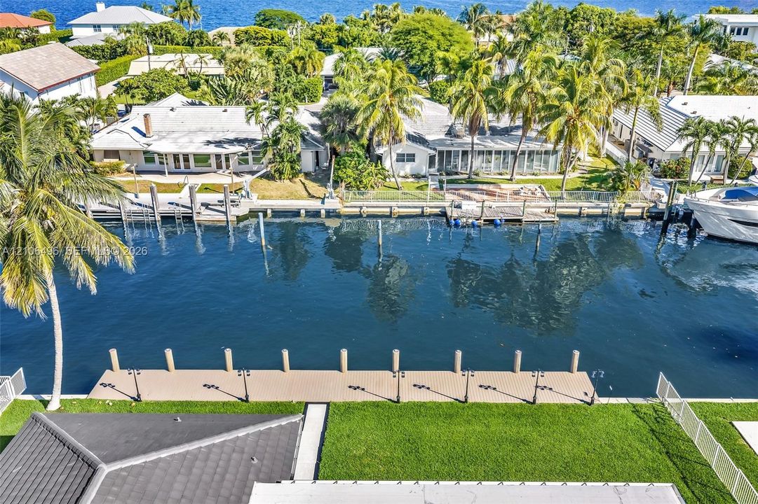 Waterfront property featuring a private boat dock, bulkheaded seawall, and manicured lawn