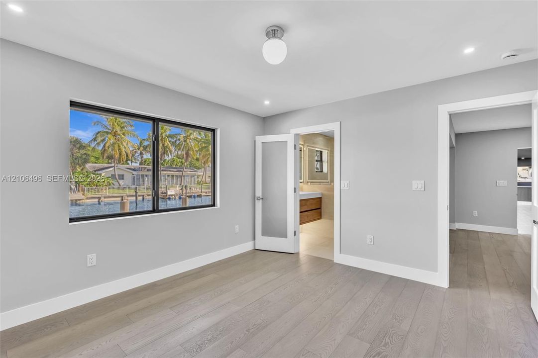 Interior space featuring wood-finish flooring, recessed lighting, a globe ceiling fixture, a large horizontal window with black trim, and a frosted glass-paneled interior door