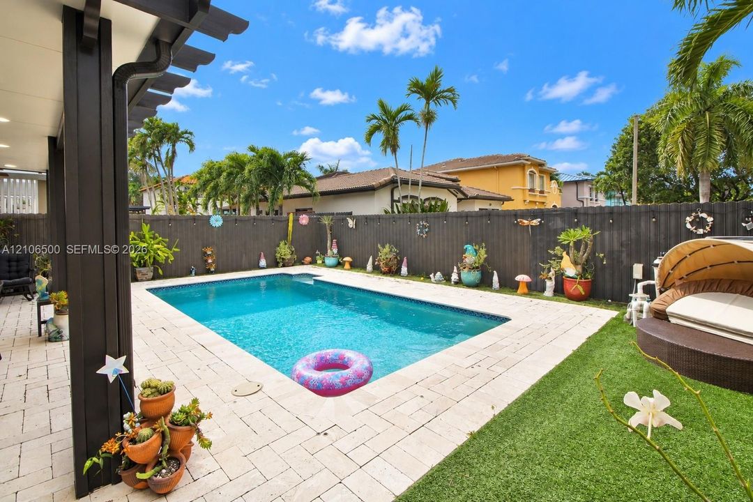 Backyard featuring a swimming pool, paved patio, synthetic turf, and perimeter privacy fencing