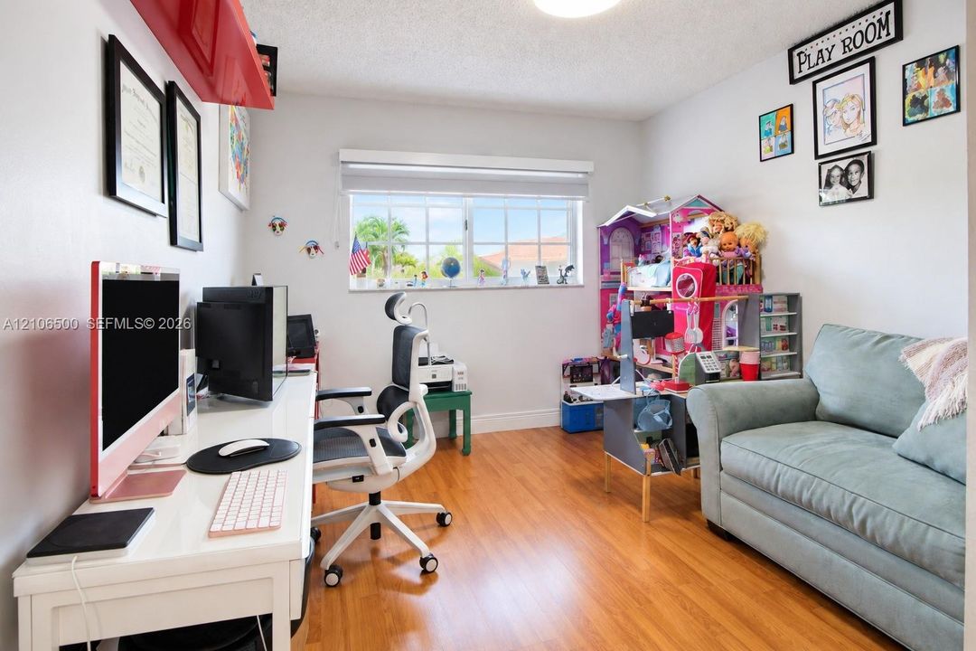 Room featuring wood-finish flooring, a neutral color palette, and a multi-pane window with a roller shade
