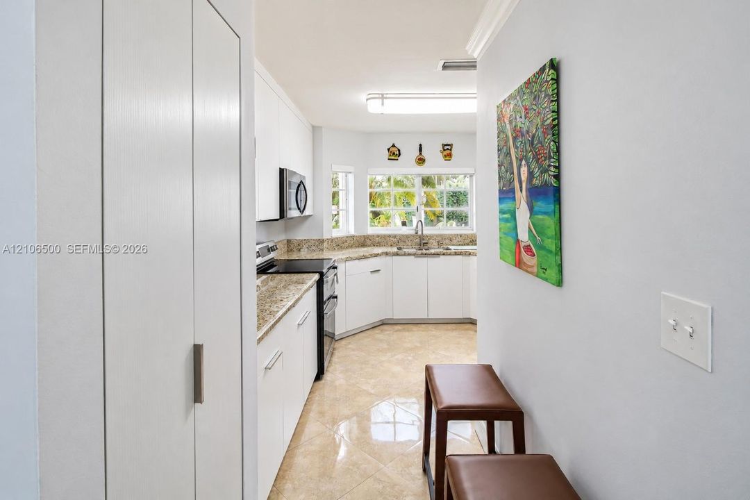 Kitchen featuring white cabinetry, stone-finish countertops, stainless steel appliances, tiled flooring, and a multi-pane window
