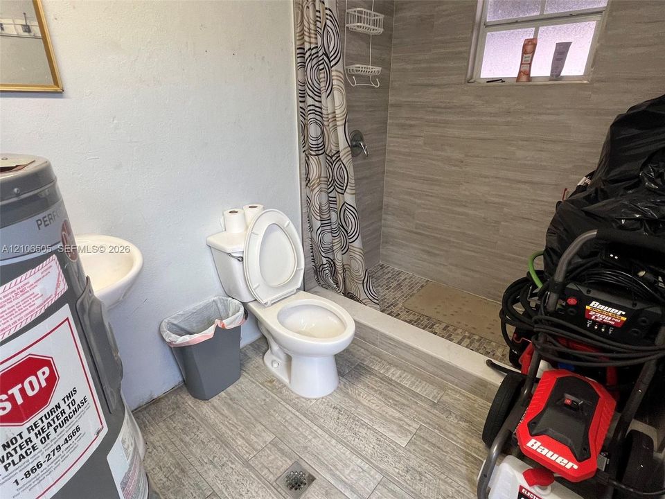 Bathroom featuring wood-finish floor tiling, walk-in shower with horizontal wall tile, and mosaic floor tile inlay