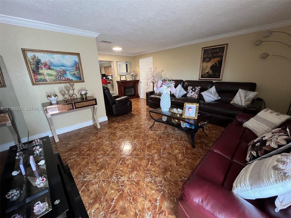 Living area featuring polished stone-look tile flooring, crown molding, and a built-in fireplace