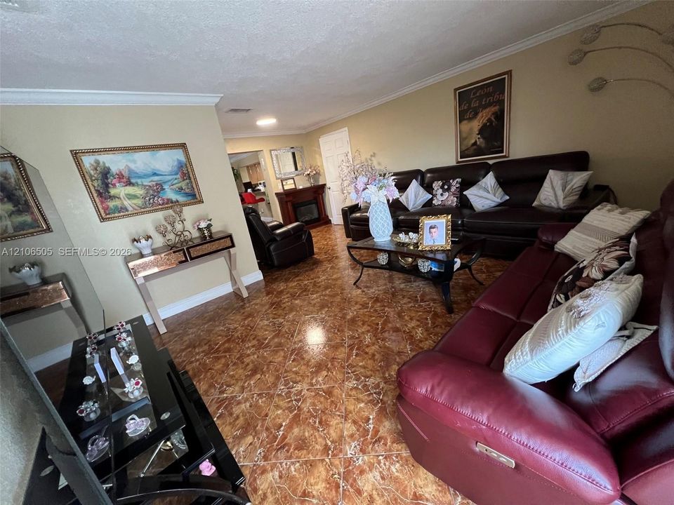 Living space featuring stone-finish tile flooring, crown molding, and a built-in decorative fireplace
