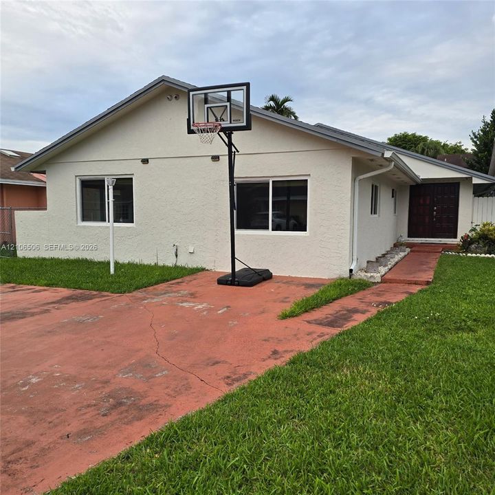 Single-story residence featuring a textured stucco exterior, dual-pane horizontal sliding windows, a concrete driveway, and a covered entry with a panelled door