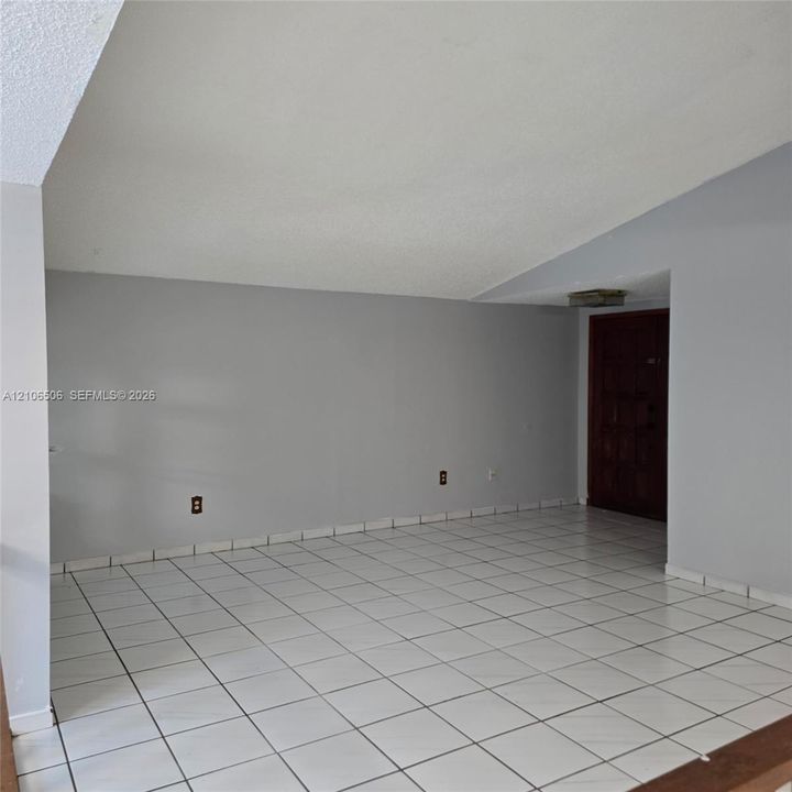 Interior space featuring vaulted ceilings, white tile flooring, and a solid wood entry door