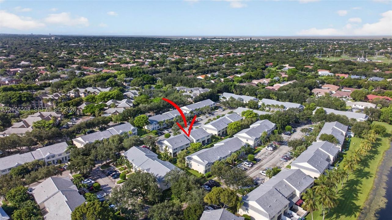 Aerial perspective of multi-family residential structure featuring a neutral-toned exterior, gabled rooflines, and mature canopy trees