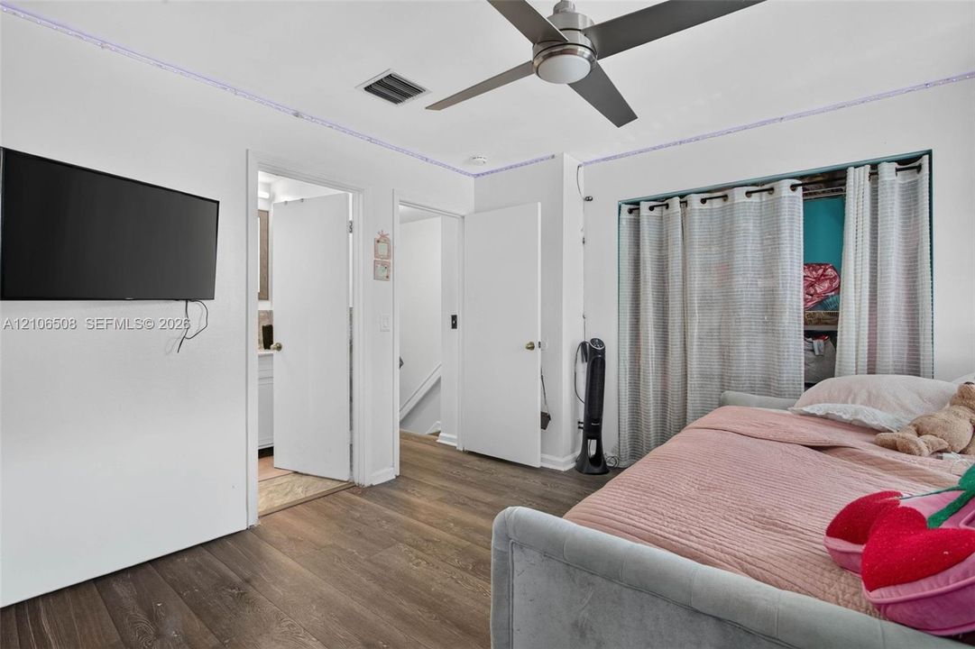 Wood-finish flooring, brushed metal ceiling fan with integrated lighting, and multiple interior passage doors