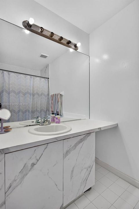 Vanity with a solid surface countertop, integrated oval sink, and stone-finish cabinetry