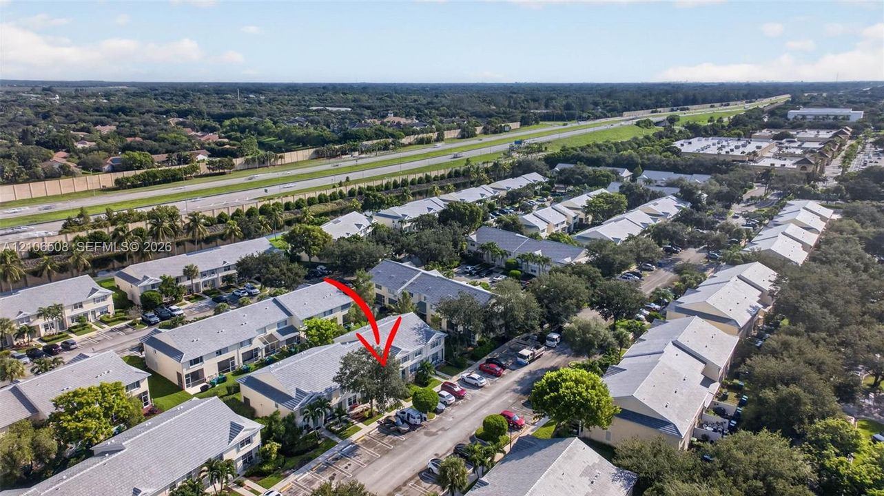 Aerial perspective of a multi-unit residential complex featuring gabled rooflines, light-toned siding, and mature landscaping