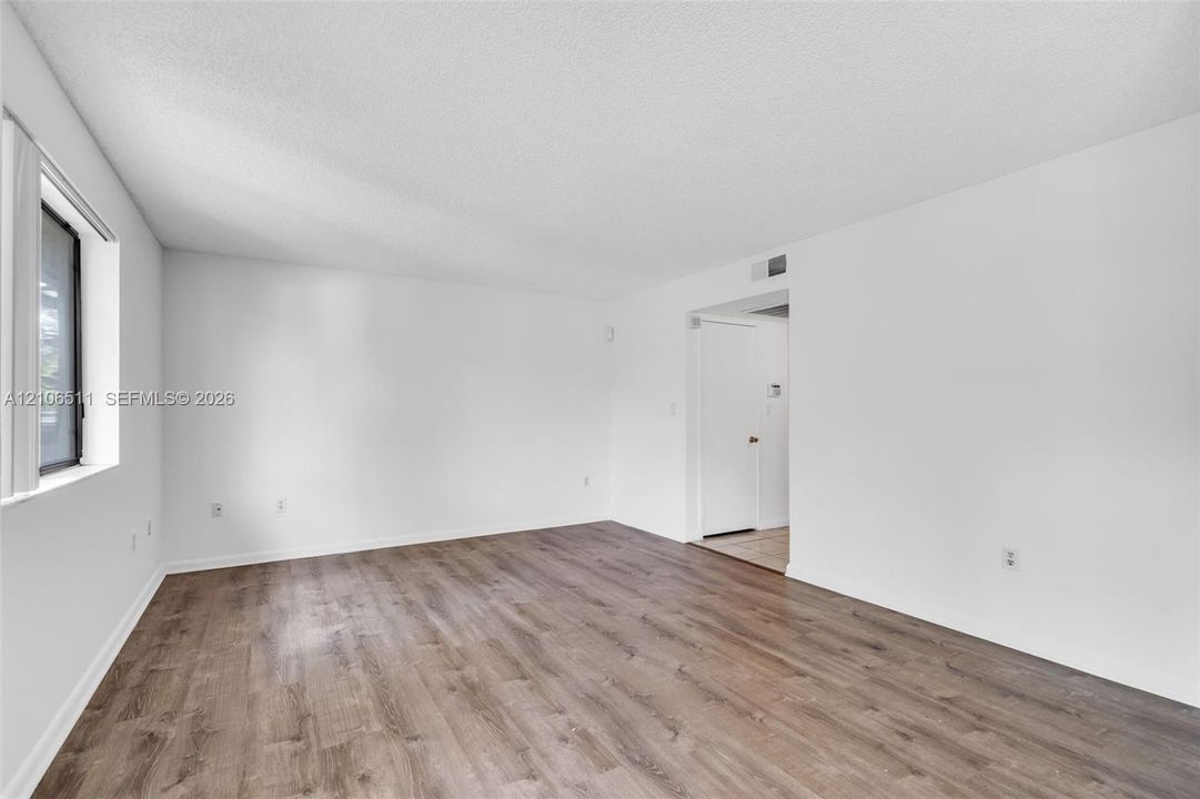 Neutral-toned interior space featuring wood-finish flooring, white walls, and a recessed window