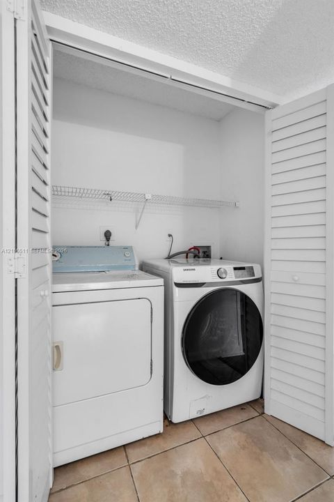 Laundry closet featuring white louvered doors, tile flooring, and built-in wire shelving