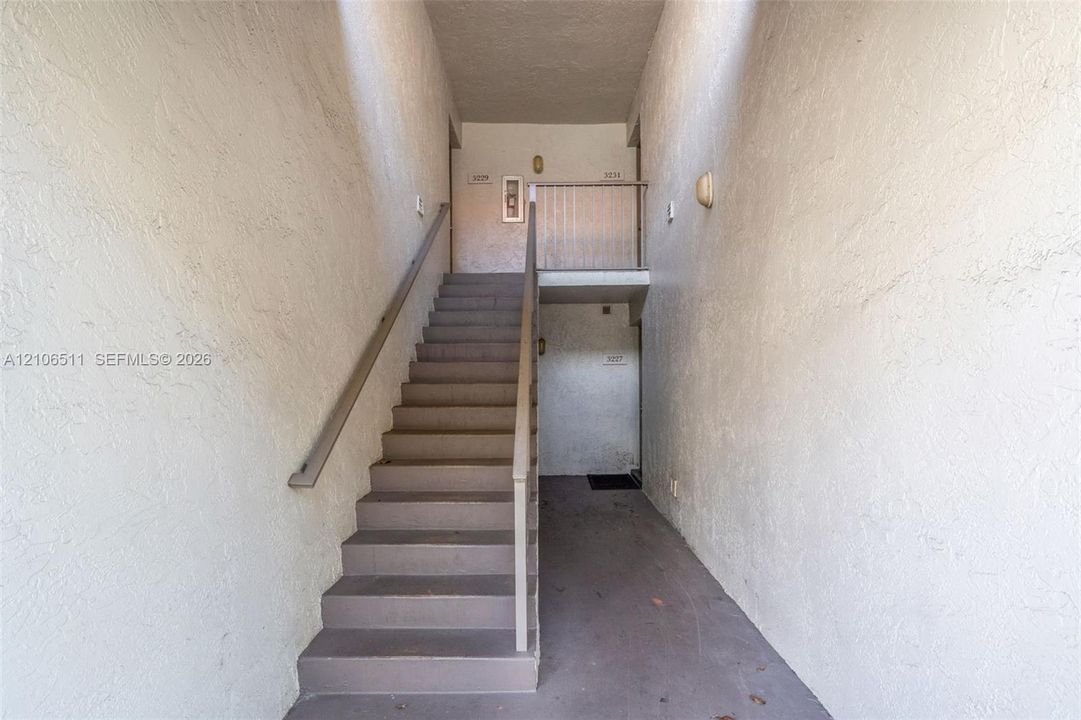 Exterior staircase featuring a neutral color palette, solid stair treads, and a metal handrail