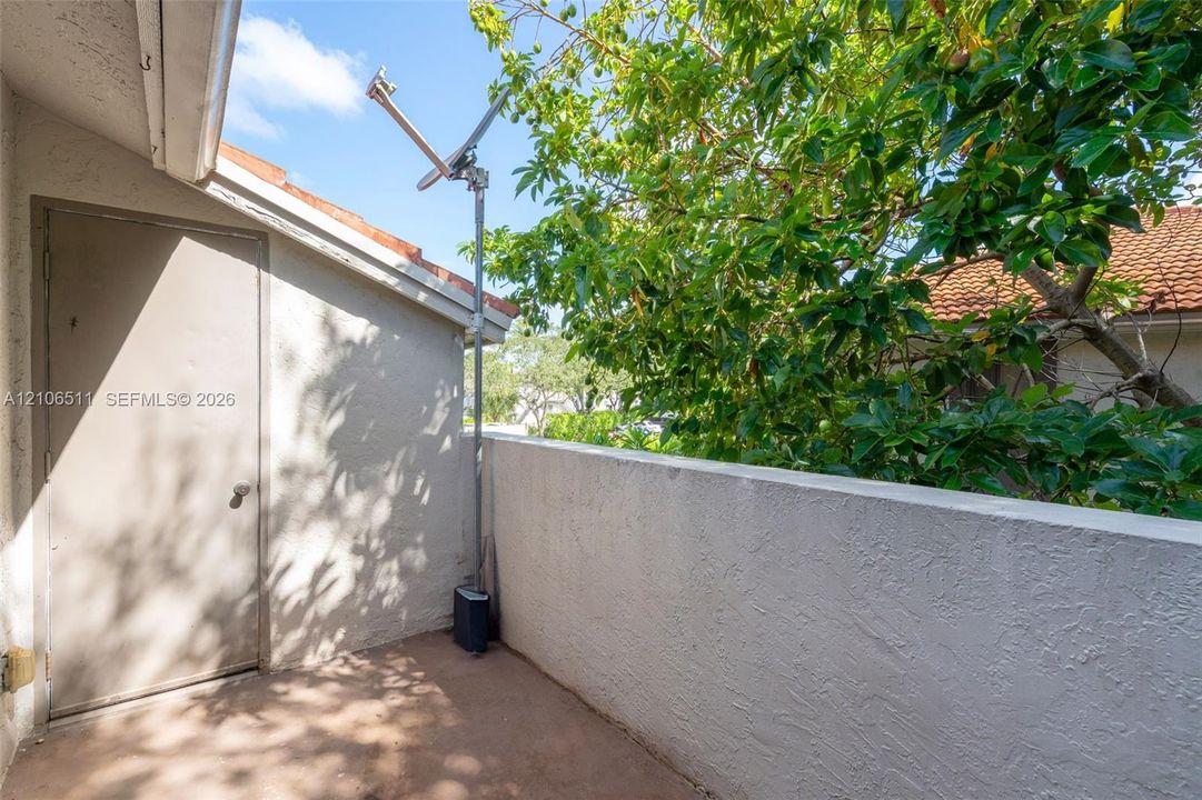 Private balcony featuring a stucco wall enclosure, concrete flooring, and a dedicated storage closet