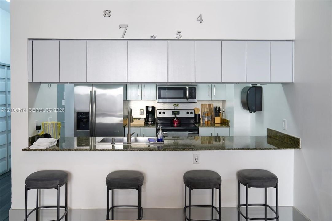 Kitchen featuring stone-finish countertops, stainless steel appliances, and wall-mounted cabinetry