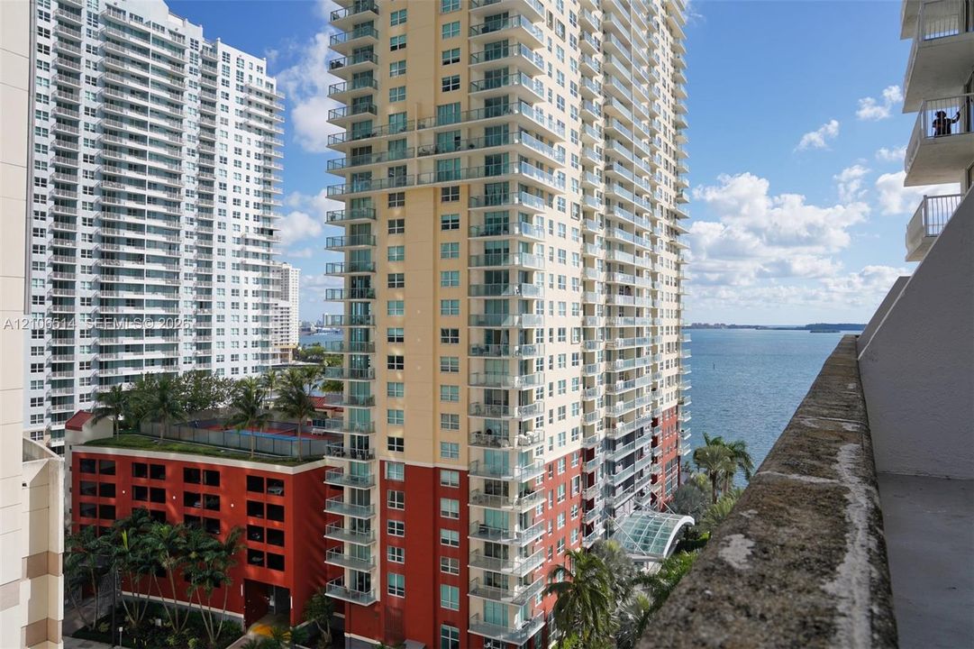 High-rise building exterior featuring private glass-railing balconies and a structural concrete terrace