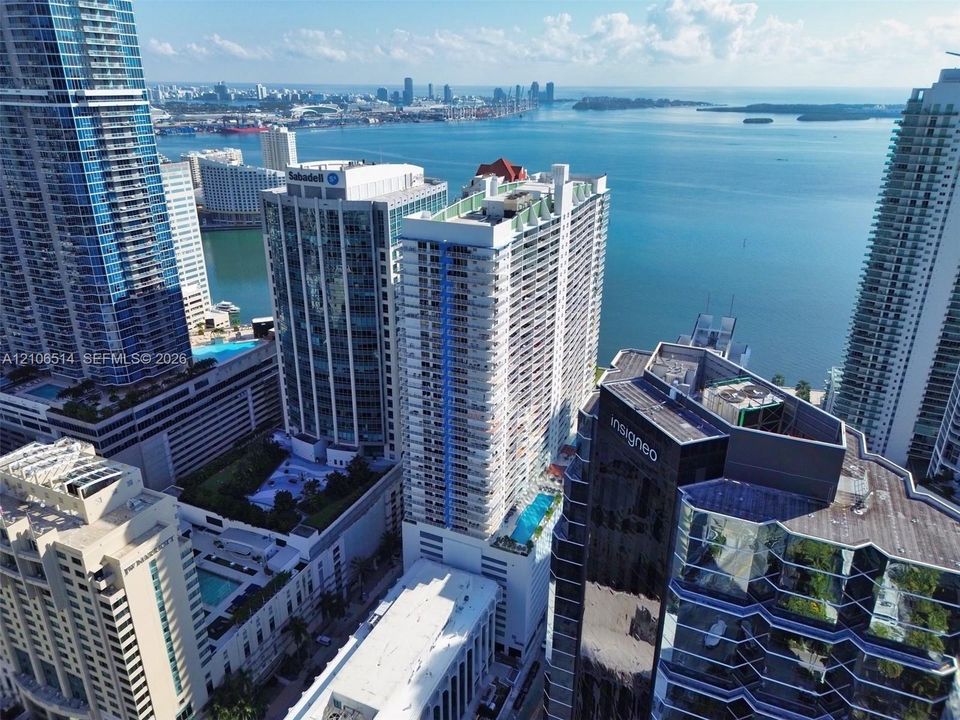 Aerial urban perspective featuring high-rise architecture, balcony-lined exterior facades, and water-front proximity