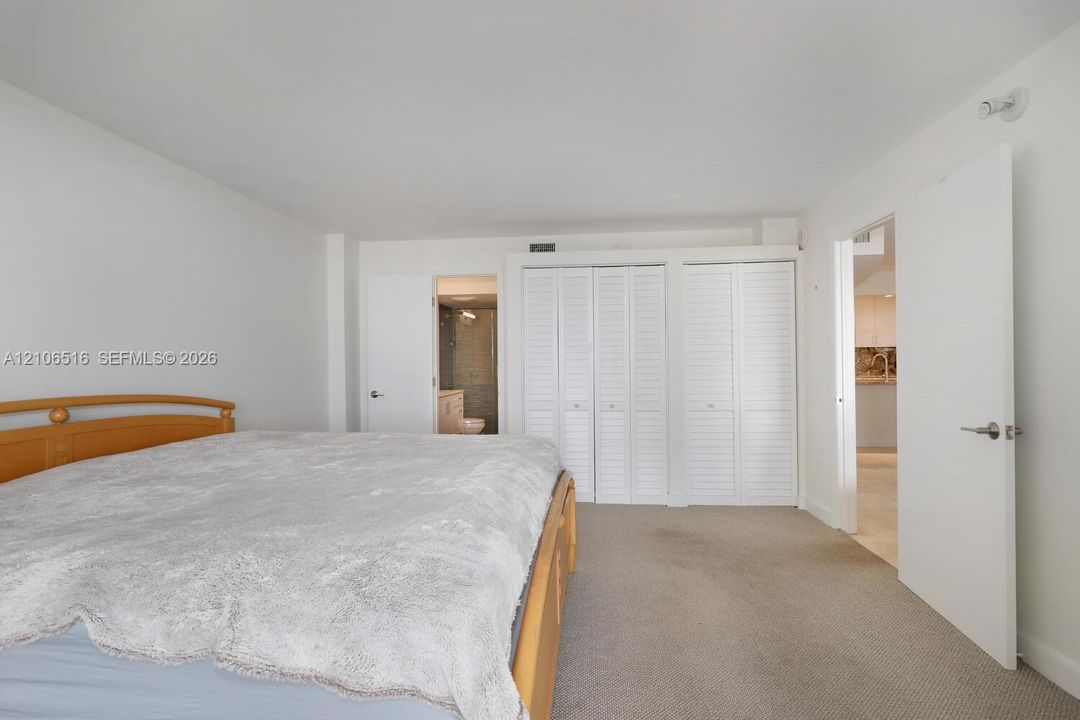 Neutral-toned carpeting, white louvered closet doors, and solid-core interior doors