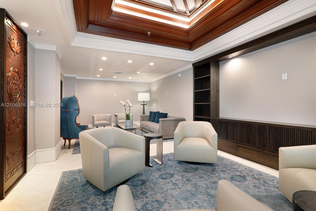 Coffered ceiling with integrated crown molding, custom dark wood-finish built-in shelving, decorative metallic door panel, recessed lighting, and tile flooring