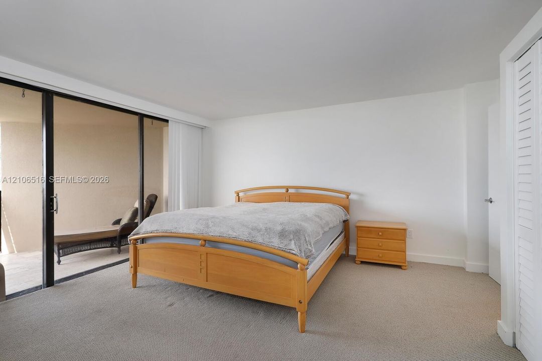 Neutral-toned carpeted flooring, floor-to-ceiling sliding glass doors, and louvered closet doors