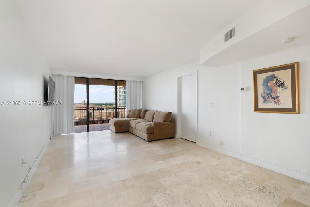 Open living area featuring large-format stone flooring, floor-to-ceiling sliding glass doors, and a private balcony