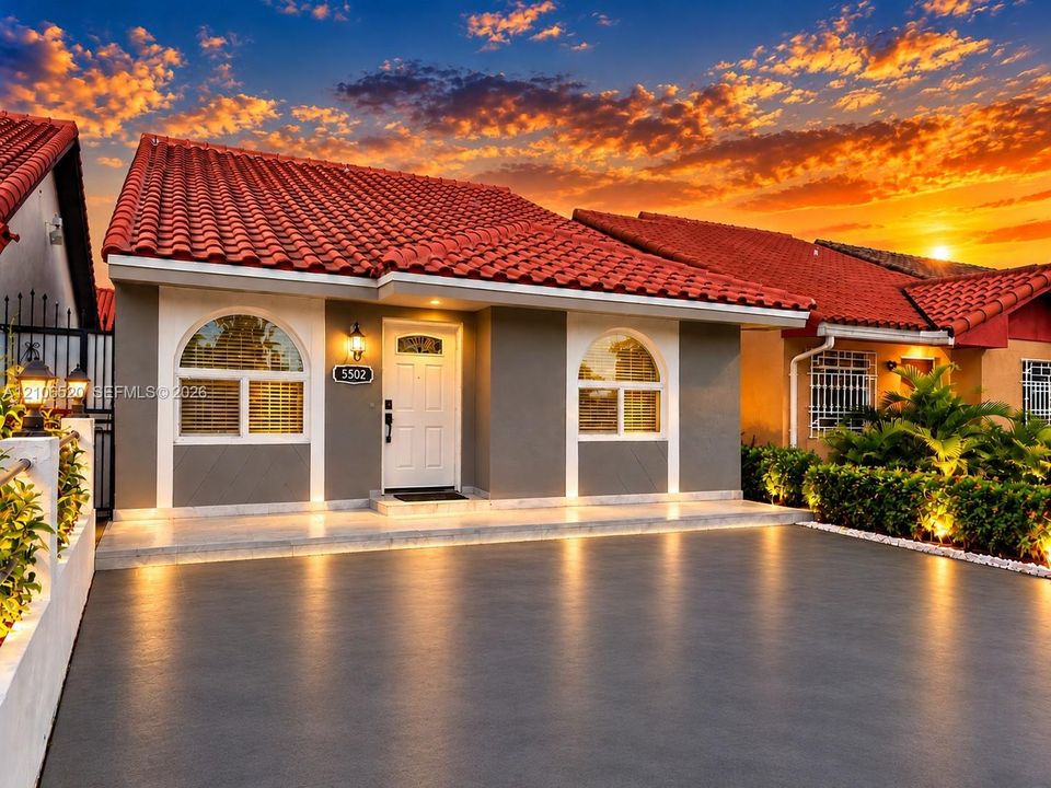 Exterior featuring a red tile roof, arched windows, and a paved driveway
