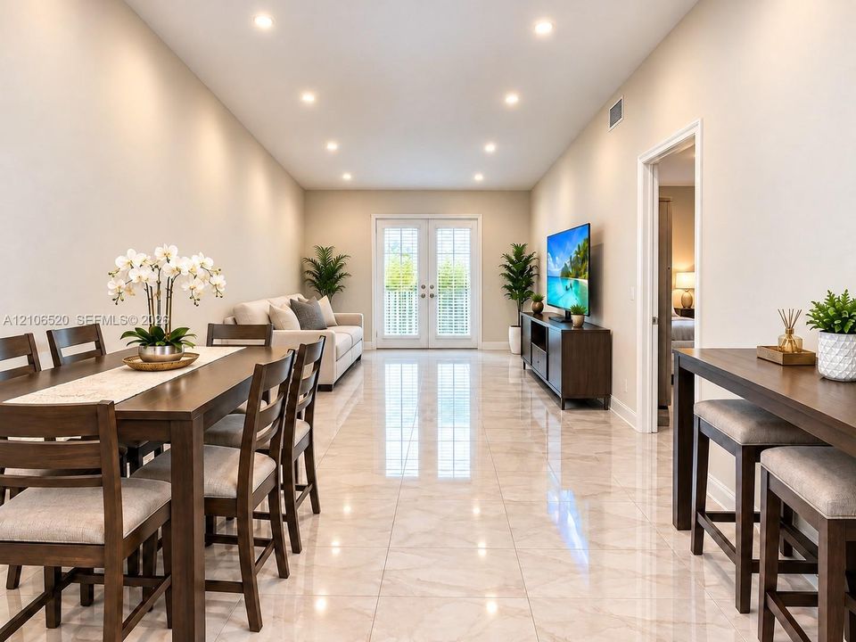 Open-concept floor plan featuring light-toned large-format tile flooring, recessed ceiling lighting, and double-paned French doors with integrated blinds