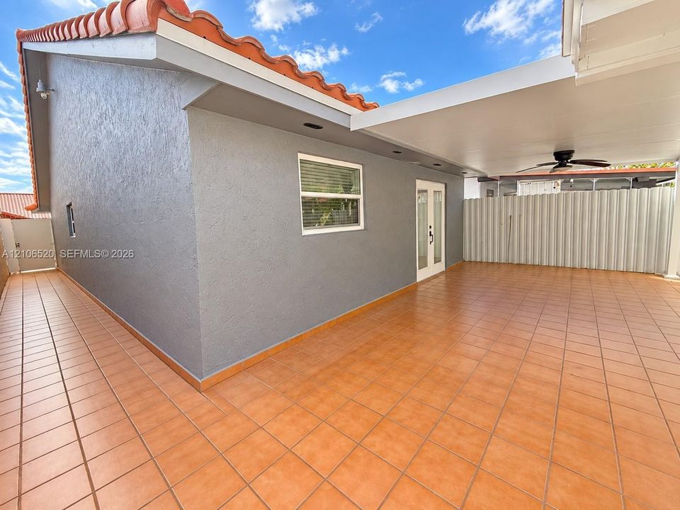 Covered patio featuring ceramic tile flooring, recessed lighting, and a ceiling fan, complemented by stucco exterior siding and a terracotta-style tile roof