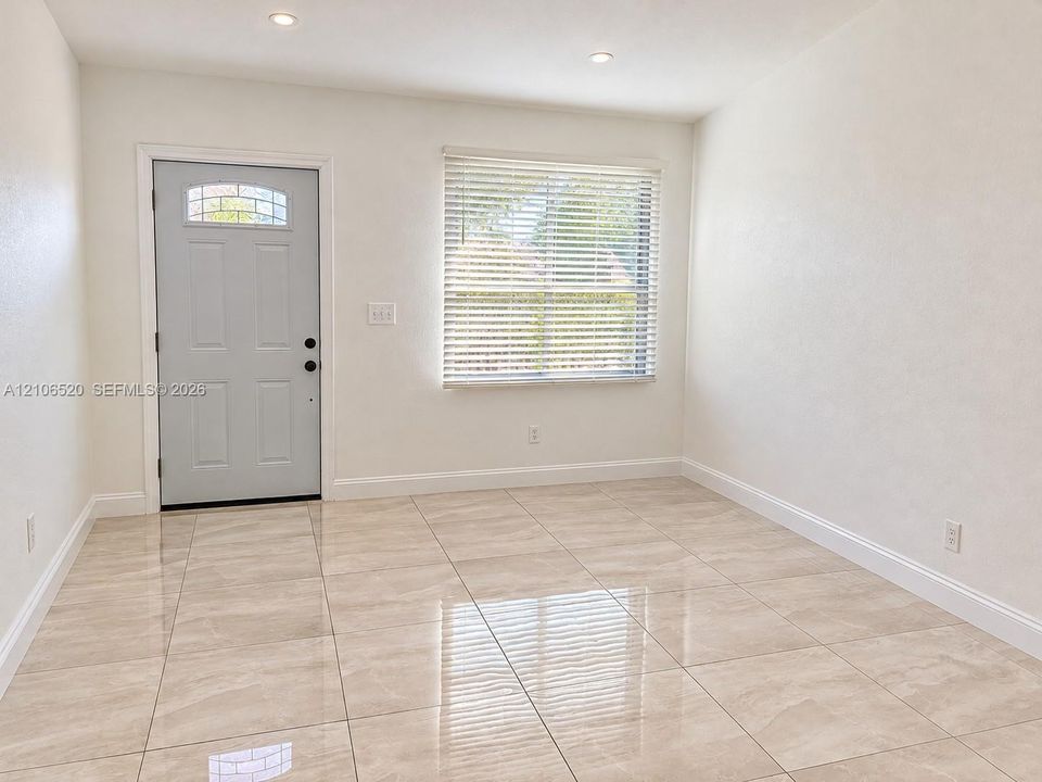 Neutral-toned tile flooring, recessed ceiling lighting, and an exterior door with a decorative glass insert