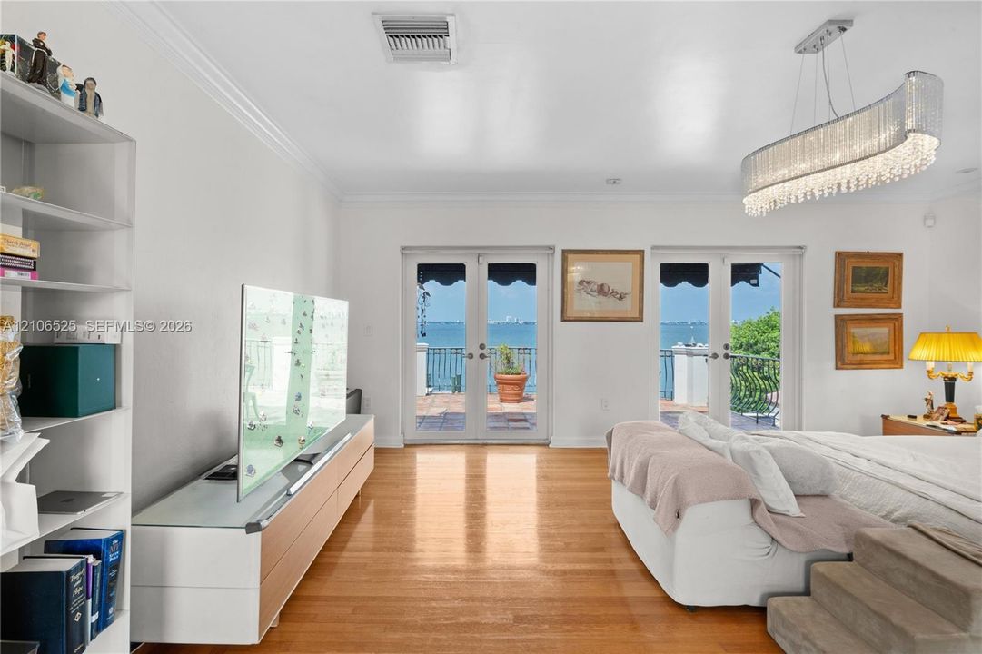 Wood-finish flooring, dual French doors, crystal-accented chandelier, and water backdrop