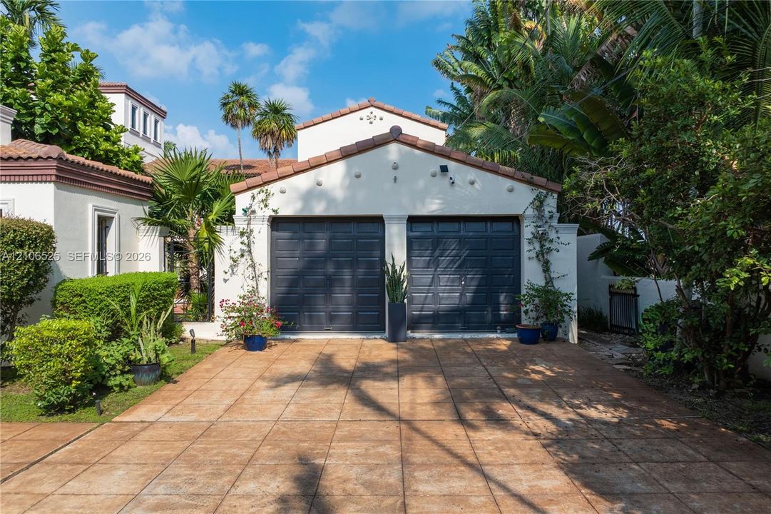Detached two-car garage with charcoal-finished sectional doors, stucco exterior, tile roofing, and a paved driveway