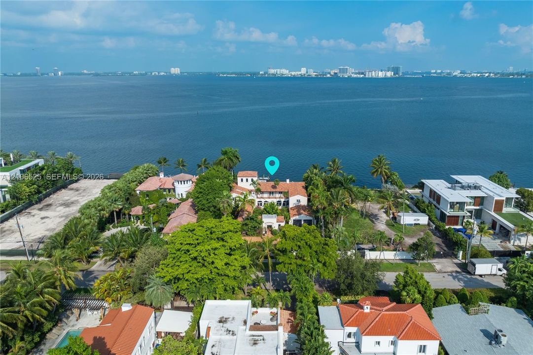 Waterfront estate featuring a tile roof, multi-level terraces, mature landscaping, and an expansive parcel